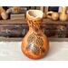 A handmade gourd vase with pinecones, branches and chickadees burned into the surface of the gourd. A wavy rim has been carved in the top.